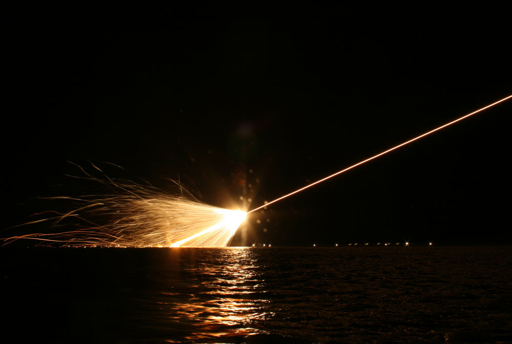 Missile explodes above water at night