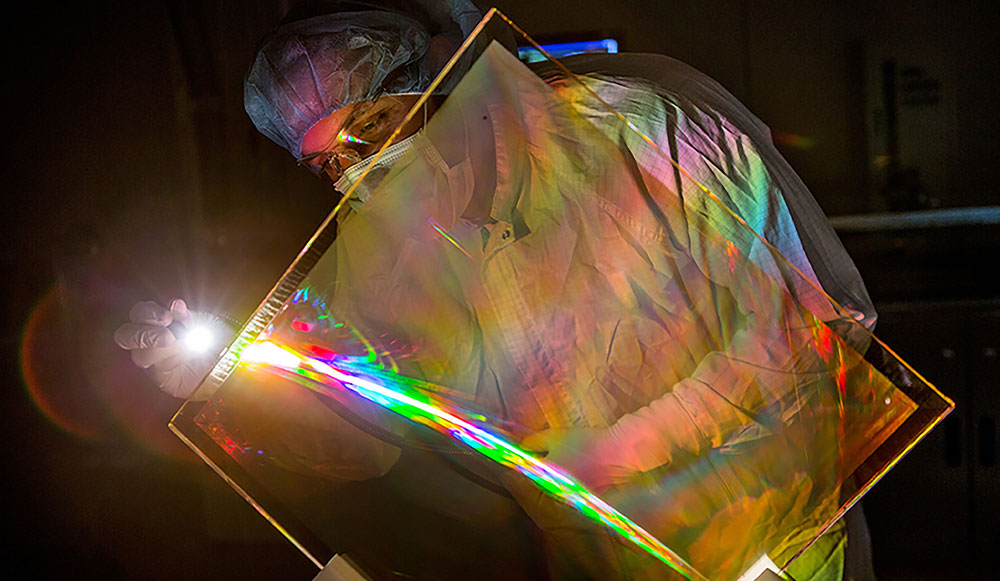An engineer inspects the antireflective coating on a NIF grating debris shield.