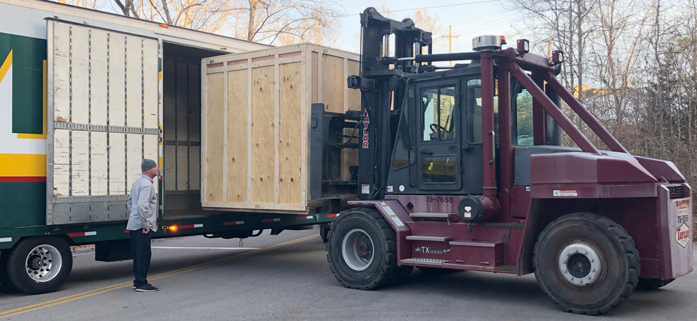 The crated detector is unloaded from a semi-truck.
