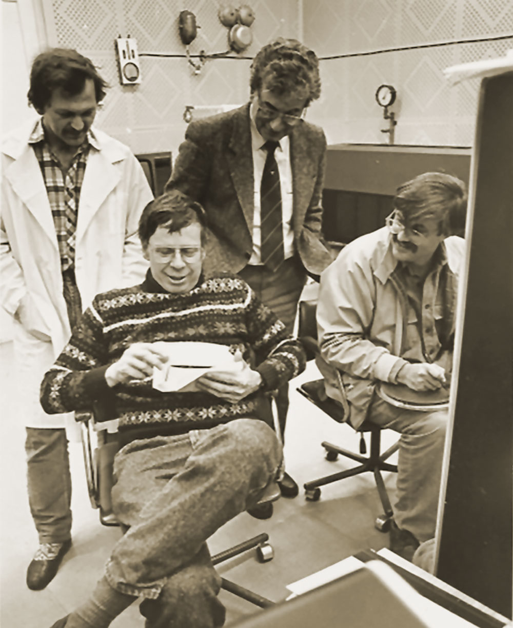 Archival photo of 4 scientists perusing paperwork and discussing their research.