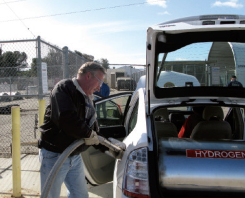 A technician fills up a vehicle’s hydrogen tank in a parking lot.
