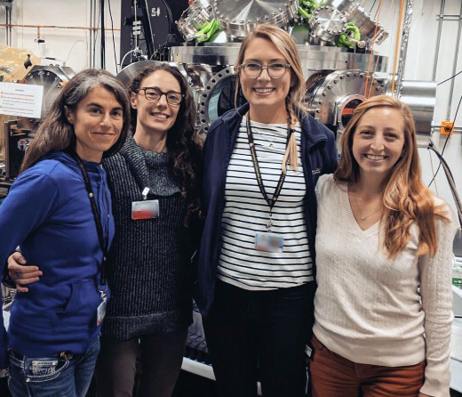 Four scientists posing in front of laboratory equipment