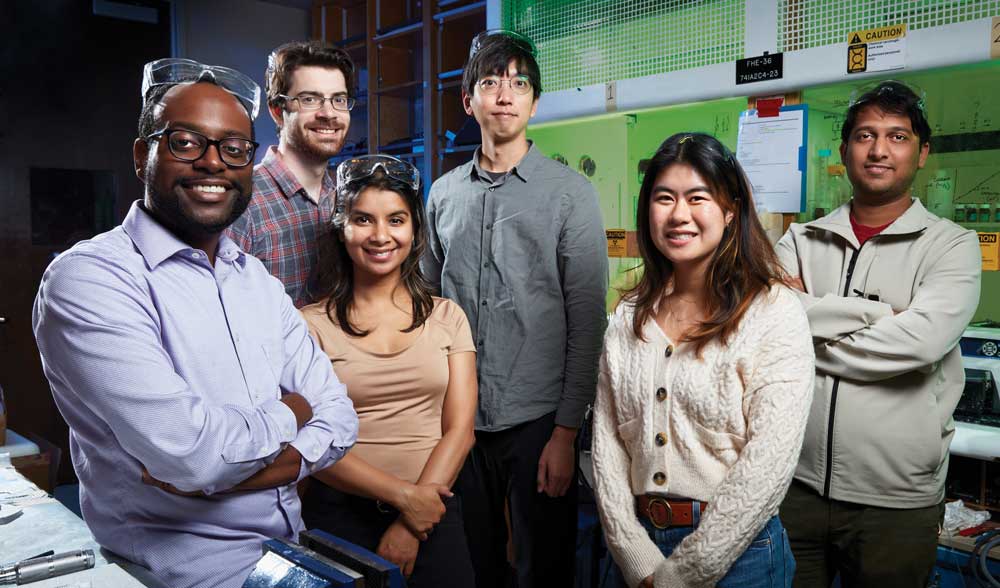 A team of six scientists pose together inside a laboratory.
