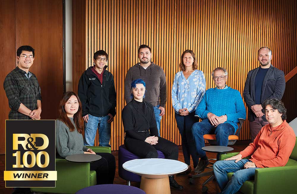 A team of nine scientists pose together inside a building.