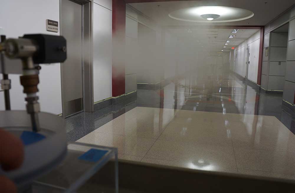 The device on the far left of the image sprays a misty compound into the corridor of a building.