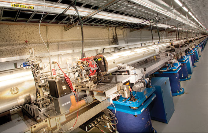 The SLAC National Accelerator Laboratory’s Linac Coherent Light Source (LCLS)—the world’s most powerful x-ray free-electron laser (XFEL)—is the first machine of its type to probe matter with hard x rays. In the LCLS Undulator Hall (shown here), short pulses of electrons travel back and forth through a 100-meter-long stretch of alternating magnets. The process produces the extremely bright x rays that are used to image structural changes in complex biomolecules, such as proteins.   