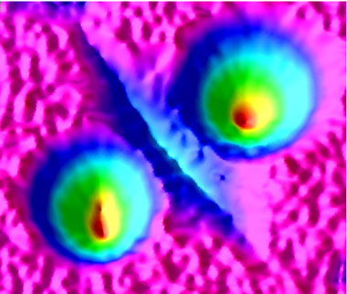 A false color, three-dimensional rendering shows two laser-induced shallow pits (LSPs) on a silicon-dioxide optical surface. A cluster of LSPs also creates the linear-like groove in the center. Typical dimensions for LSPs are up to a few tens of micrometers in width and hundreds of nanometers in depth.  