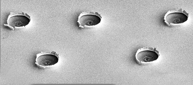 A scanning electron microscopy image shows the free surface of an iron sample after five shots from an ultrafast laser. The craters are the result of compression waves generated by the intense laser energy applied to the reverse surface. (Image by Liam Krauss.)