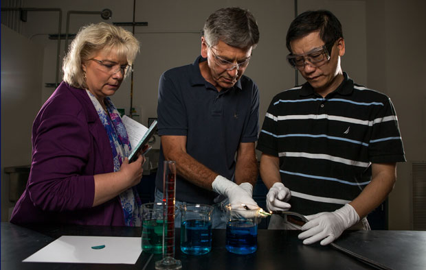 Livermore researchers (from left to right) Kathleen Schaffers, Paul Ehrmann, and Roger Qiu observe the infrared-blocking properties of various dopants in aqueous solutions.
