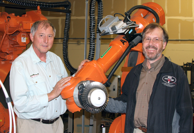 Lloyd Hackel (left) and Brent Dane stand with a robot used in laser peening to strengthen critical parts for aviation and other industries. The duo successfully commercialized a laser peening technology—marketed as the Lasershot Peening System—used around the world in airplane fuselages and turbines, as well as in turbines for electric power generation. (Photograph by Julie Russell.) ”   