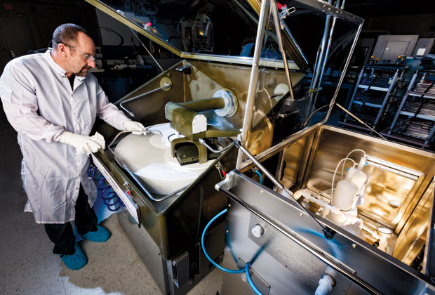 Steele inspects the slurry feed used by the prototype CISR (convergent, initial-surface-independent, single-iteration, rogue-particle-free) polisher. To the right of the polisher is the slurry filtration unit. (Photo by Damien Jemison.)