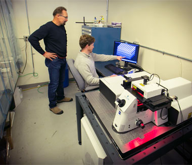 Livermore scientists James Oakdale (seated) and Juergen Biener examine a three-dimensional printed foam design before fabricating it using the Laboratory’s Nanoscribe Professional GT printer. 