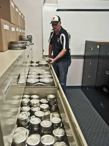 Film expert Jim Moye selects one of the thousands of film canisters queued for scanning and analysis. (Photo by Lee Baker.)