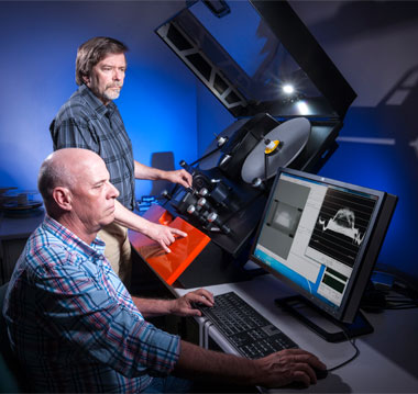 Filmmaker and documentarian Peter Kuran (standing) operates the Golden Eye II scanner, while Moye reviews a scanned image’s digital fidelity and optical density distribution. (Photo by Randy Wong.) 
