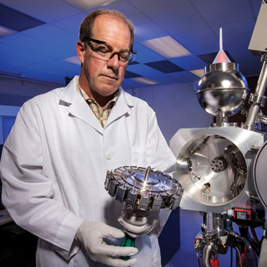 Borg is shown holding the sample wheel of a thermal ionization mass spectrometry system, which the cosmochemistry team uses to measure isotope ratios.